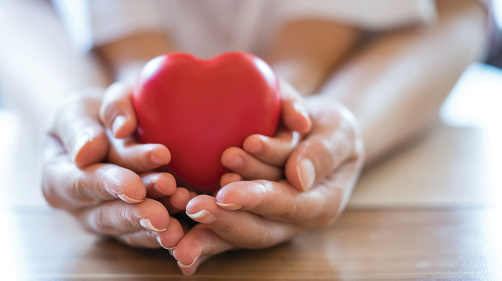 Adult hands holding child hands holding a red heart