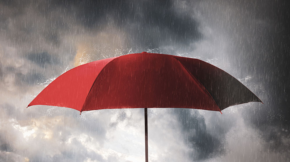 Red umbrella shielding from rain from heavy storm.