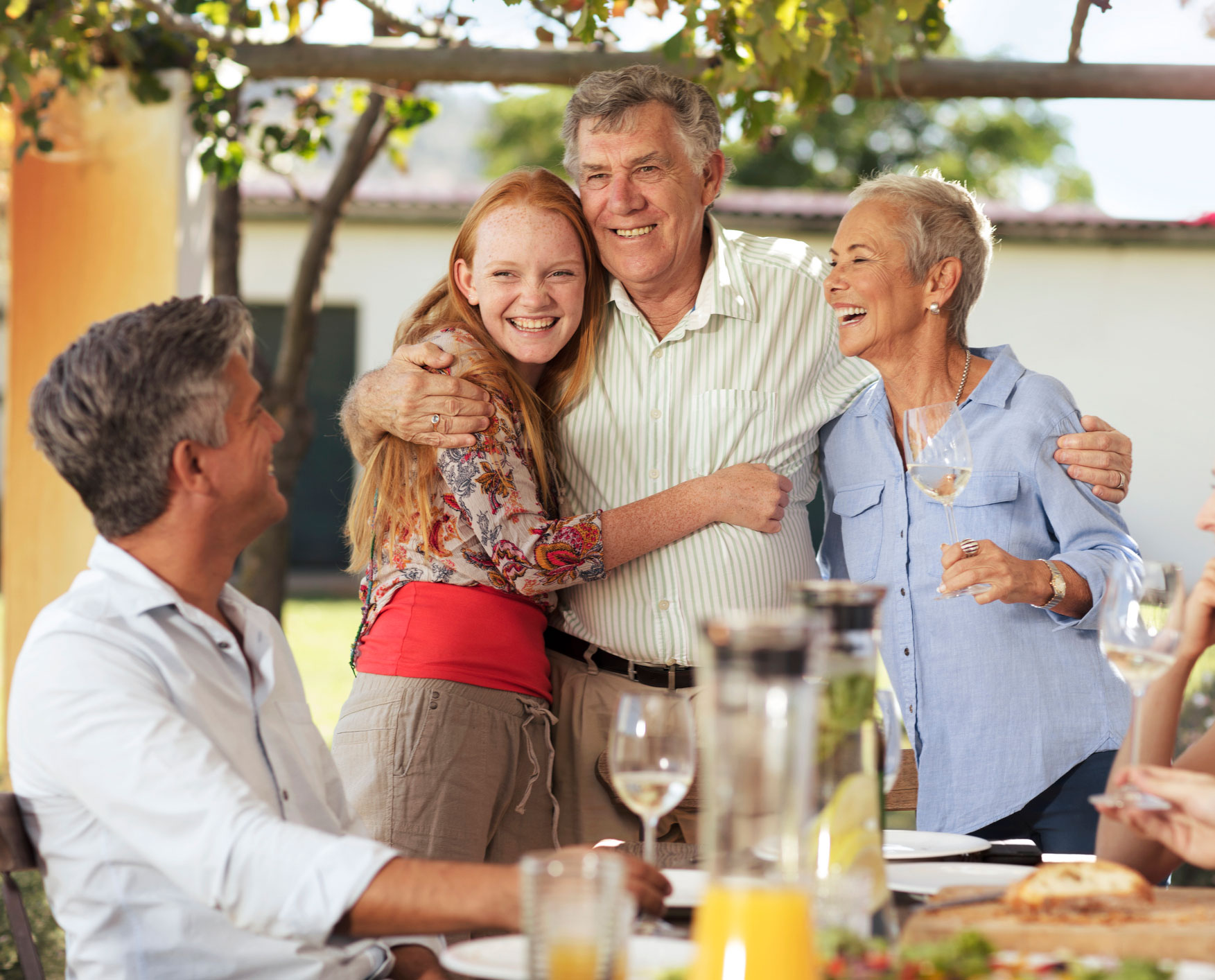 Multi-generational family hugging and smiling at a dinner together