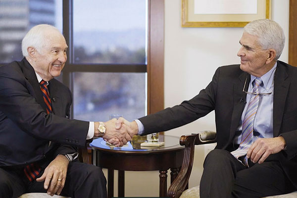 Earl Wright and Tommy Arnold shake hands as merge firms.