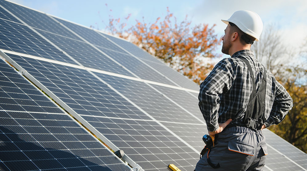 Man with hardhat surveying solar panel array