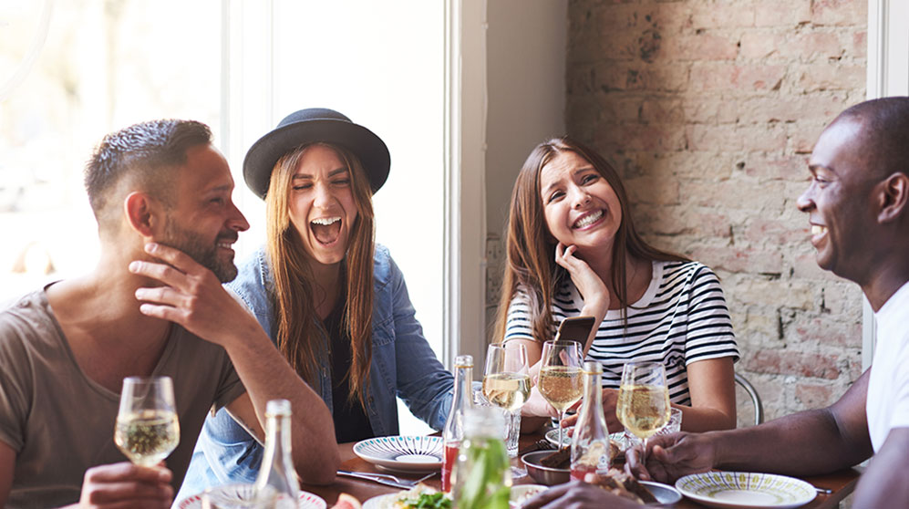 happy friends at a restaurant using zelle