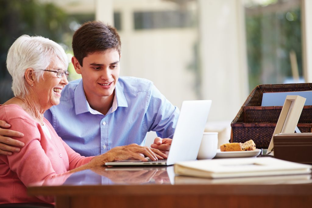 Grandmother and grandson working together on a laptop computer.